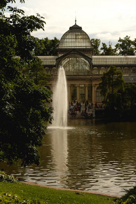 Photograph of the ornate glass and metal structure of Crystal Palace Park, showcasing its intricate architectural details with arched windows and a large domed roof, set against a clear blue sky. The image highlights well-maintained surfaces, clean glass panes, and polished metallic elements, emphasizing the importance of surface cleaning and maintenance for historic buildings. Cleaner Crystal Palace specializes in deep cleaning and sanitisation of such surfaces to preserve architectural beauty, with visible reflections and bright, dust-free surfaces indicative of professional cleaning efforts.